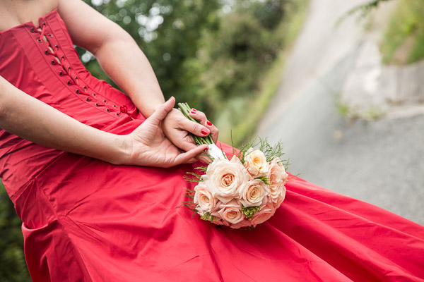 Originale vestido de novia de color rojo con un precioso y elegante ramo.
